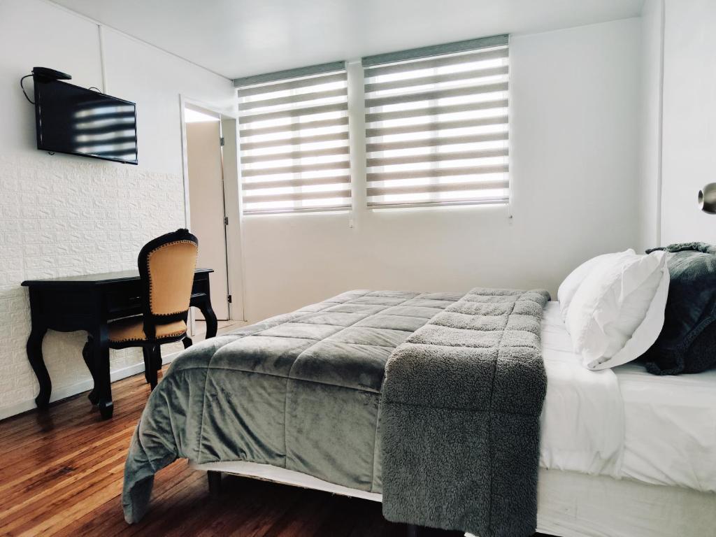 a bedroom with a bed and a desk and a window at Hotel Muros Quito in Quito