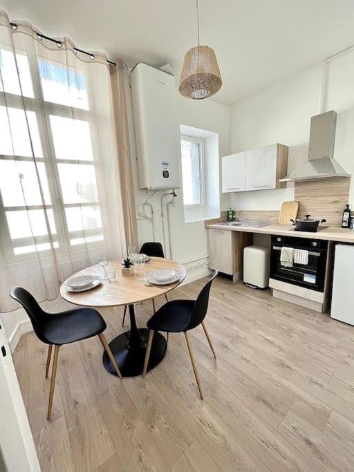 une cuisine avec une table et des chaises dans une pièce dans l'établissement L'Aventurine - Romans, à Romans-sur-Isère