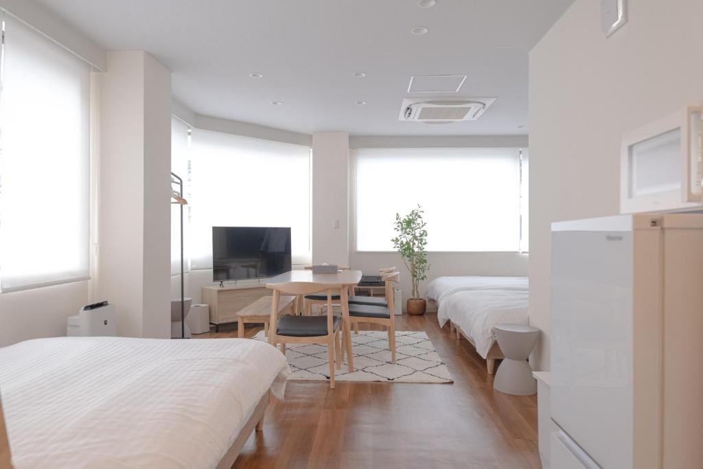 1 Schlafzimmer mit 2 Betten, einem Tisch und einem TV in der Unterkunft RIVER VILLAS HIROSHIMA - Vacation STAY 24194v in Hiroshima