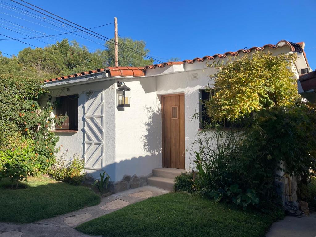 mały biały dom z brązowymi drzwiami w obiekcie La Casita w mieście La Cumbre