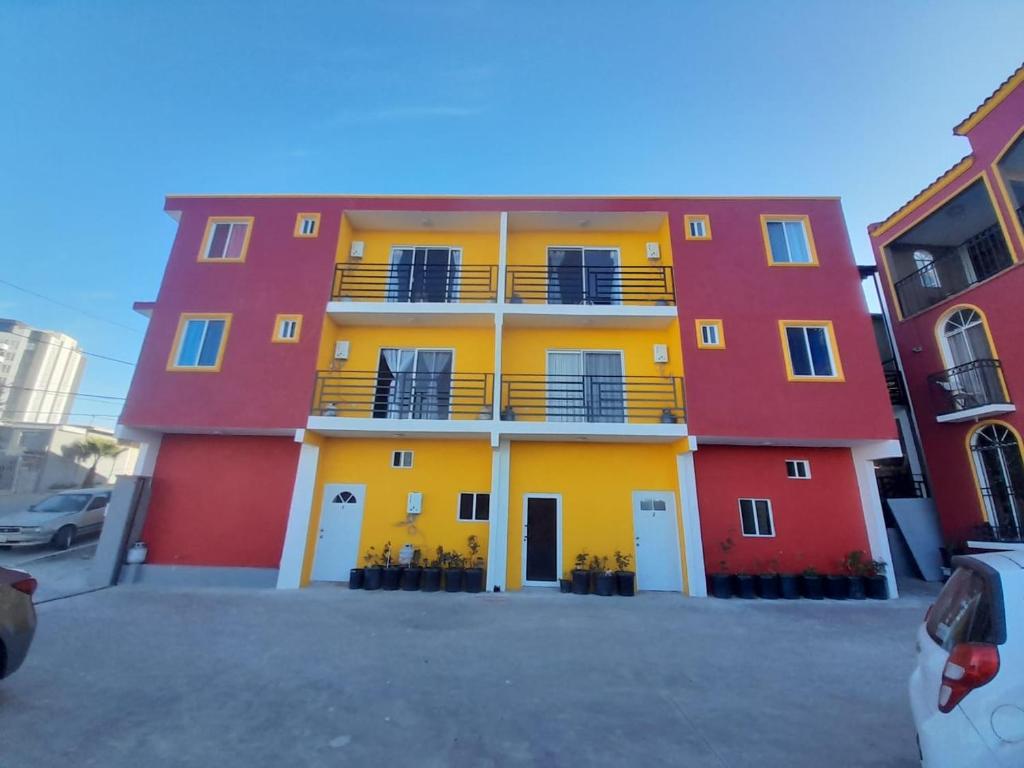 un bâtiment rouge orange et jaune avec un parking dans l'établissement Departamentos velasco, à Tijuana