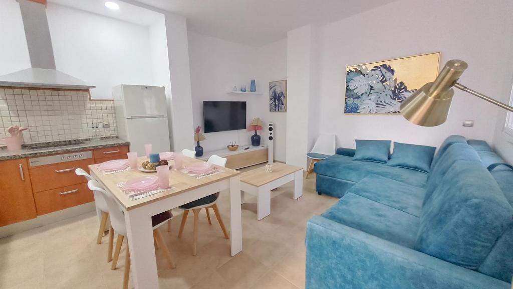 a living room with a blue couch and a table at Apartamentos TrianaSol in Seville