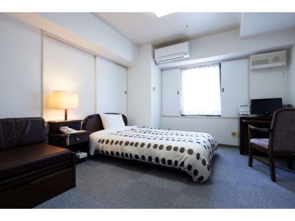 a bedroom with a bed and a couch and a desk at Hotel Alpha Inn Akita - Vacation STAY 67278v in Akita