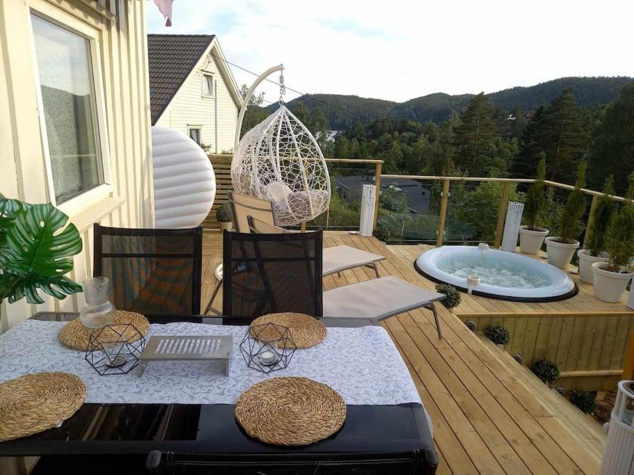 una mesa y sillas en una terraza con bañera de hidromasaje en Hytte Sørlandet med spa, en Froland Verk