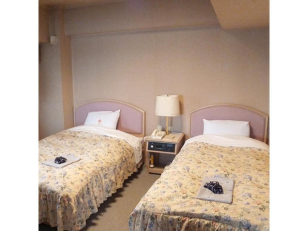 sypialnia z 2 łóżkami i stolikiem nocnym z lampką w obiekcie Hotel Alpha Inn Akita - Vacation STAY 67285v w mieście Akita