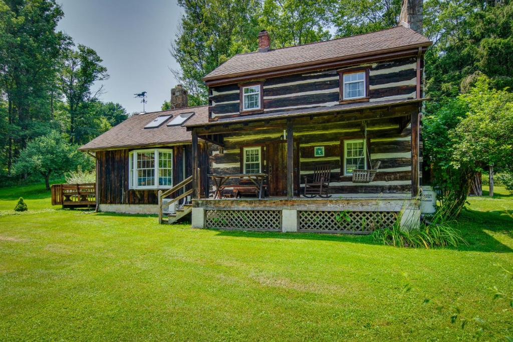 una casa vieja con un gran patio delante de ella en Historic Morrisdale Area Cabin with Deck and Fireplace, 