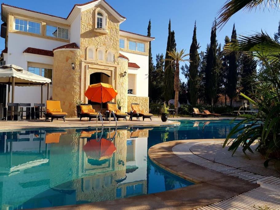 een huis en een zwembad met een parasol bij Villa piscine Agadir in Agadir