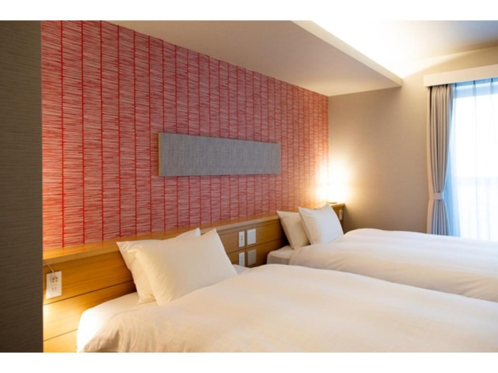 um quarto de hotel com duas camas e uma parede com azulejos vermelhos em Hotel Celeste Shizuoka Takajo - Vacation STAY 94099v em Shizuoka