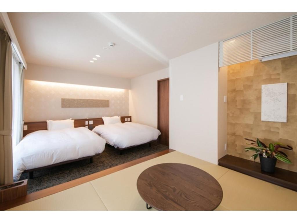 1 dormitorio con 2 camas y mesa de madera en Hotel Celeste Shizuoka Takajo - Vacation STAY 94075v en Shizuoka