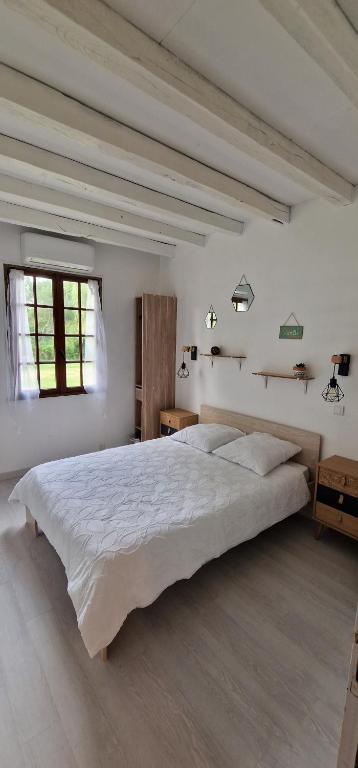 a white bedroom with a large bed and a window at Maison charmante climatisée avec aire de jeu à 35 minutes de Disneyland Paris 
