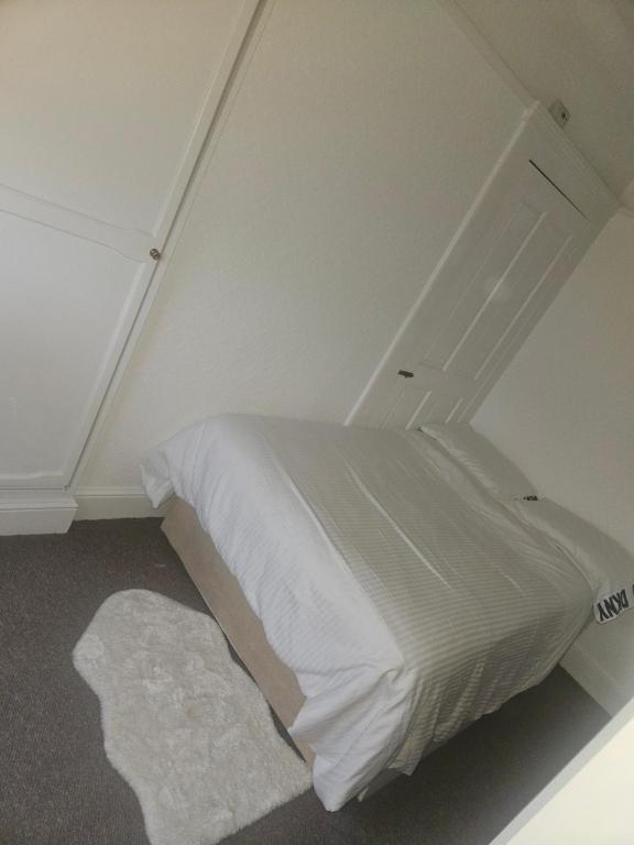 uma pequena cama branca num pequeno quarto em Diamond em Abbey Wood