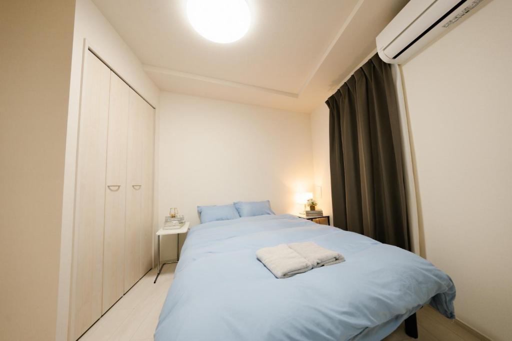 a bedroom with a large bed with blue sheets at FL Rejidence Shinjuku 2 - Vacation STAY 15199 in Tokyo