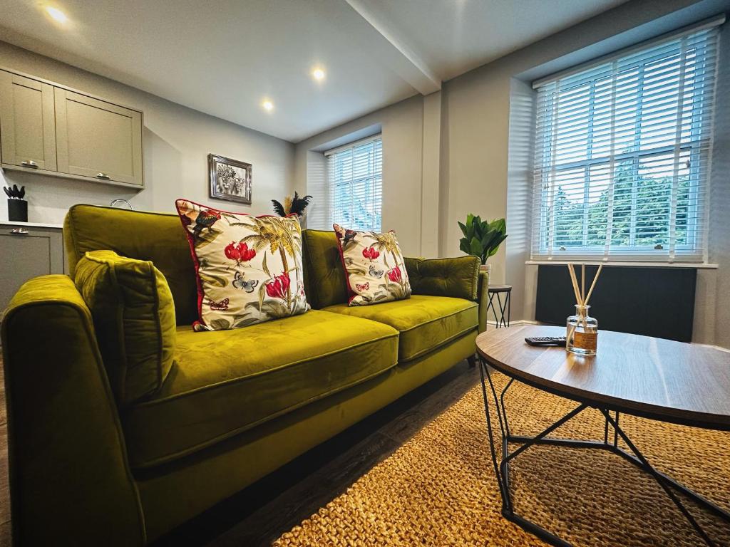 a living room with a green couch and a table at 1 West End Boutique Apartment in Bowness-on-Windermere