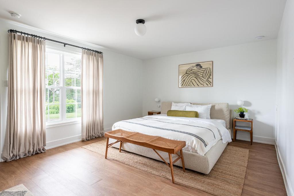 a white bedroom with a bed and a window at Evangeline in Grand pré