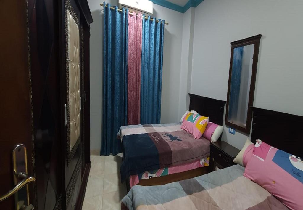 a bedroom with two beds and a mirror at M&H Apartment in Dumyāţ al Jadīdah