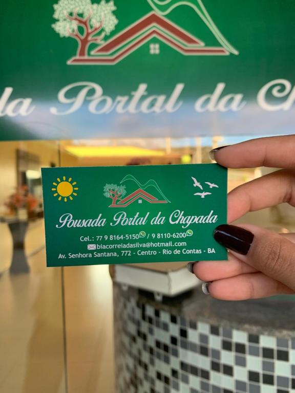 una persona con una tarjeta de visita frente a una mesa en Pousada Portal da Chapada, en Rio de Contas