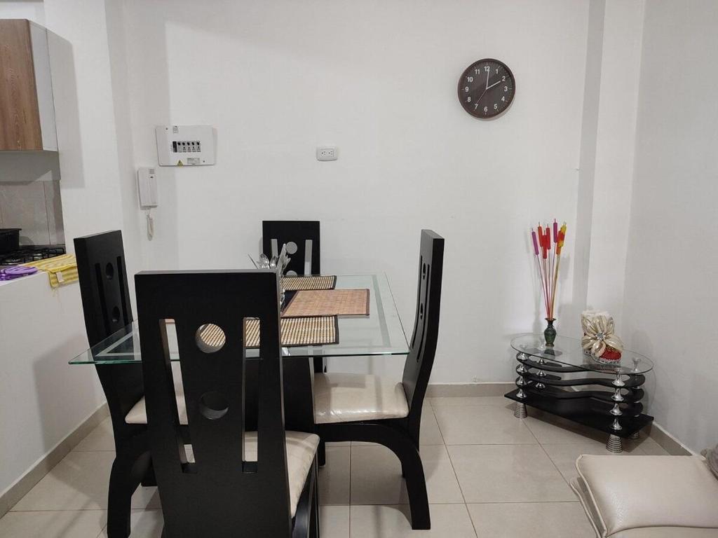 een eettafel met stoelen en een klok aan de muur bij GURUS FR | Apartamento cerca al Aeropuerto y Terminal 2 Hab in Pereira