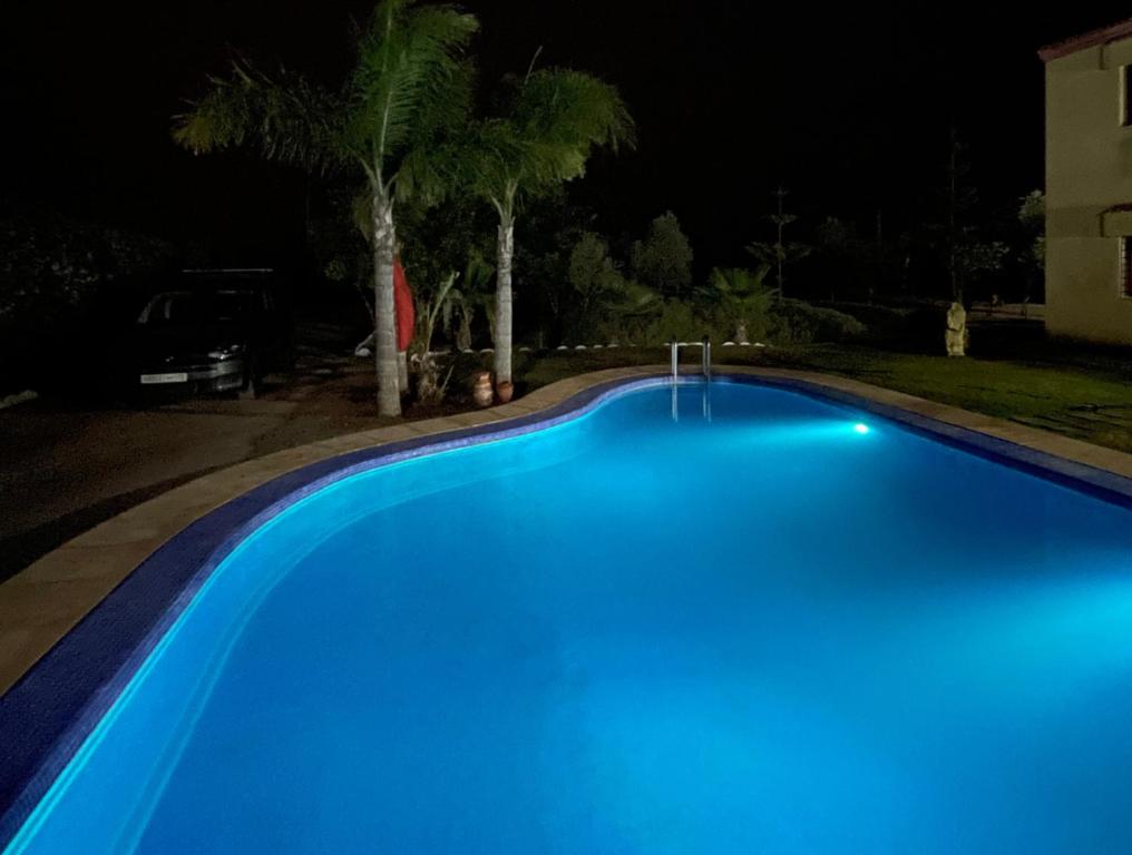 a blue swimming pool at night at Villa avec Piscine, Terrain de Foot et Aire de Jeux pour Enfants in Bir Jedíd Saint-Hubert