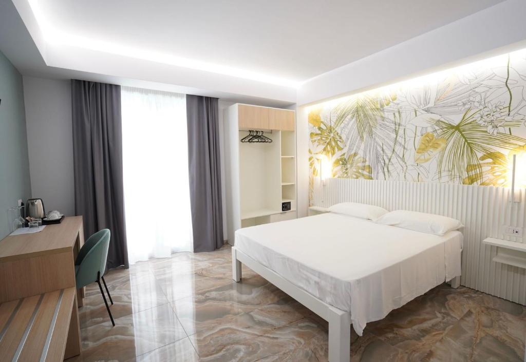 Harmony Tropea Rooms & Suites في تروبيا: غرفة نوم بسرير ابيض ولوحة على الحائط
