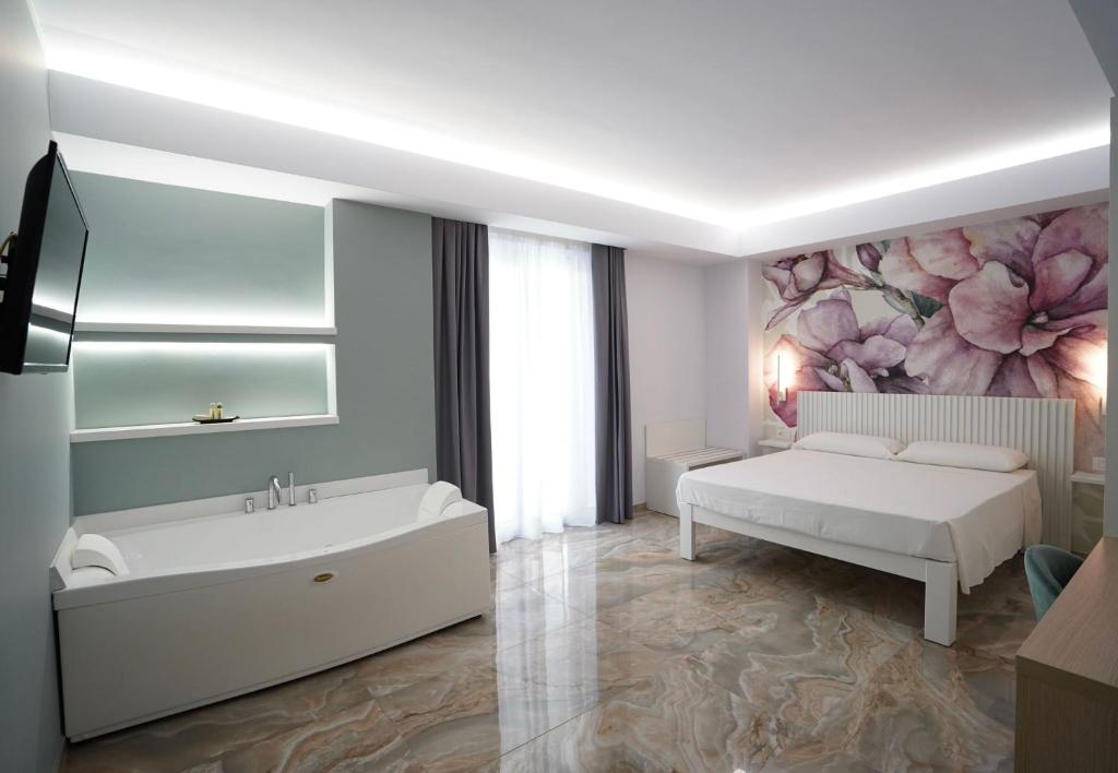 ein weißes Schlafzimmer mit einem Bett und einer Badewanne in der Unterkunft Harmony Tropea Rooms & Suites in Tropea