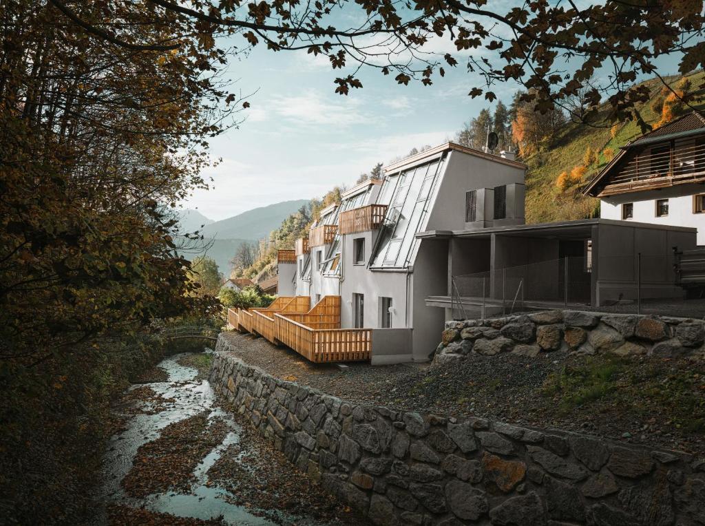 ein Haus auf einem Hügel neben einem Fluss in der Unterkunft Mondholz - Urban Inn 24-7 in Innsbruck