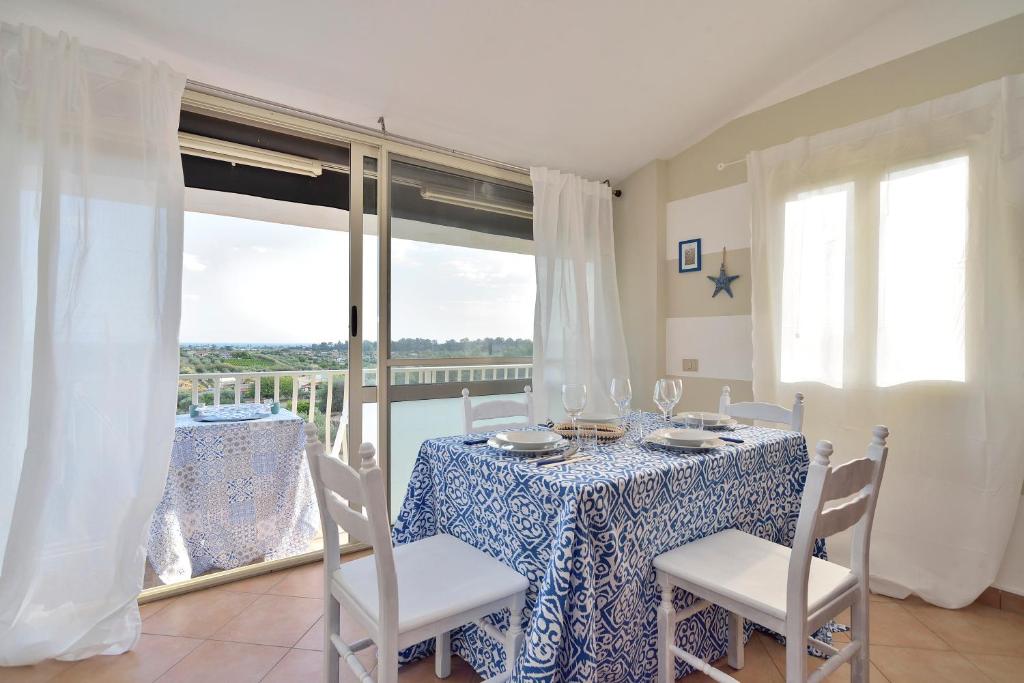 una sala da pranzo con tavolo, sedie e finestra di Bellavista Apartment a Santa Maria del Focallo