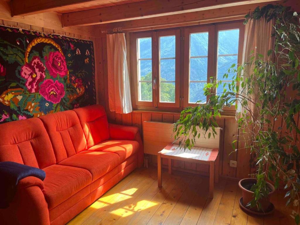 een woonkamer met een rode bank en een raam bij Appartamento accogliente di montagna a Cavagnago in Faido