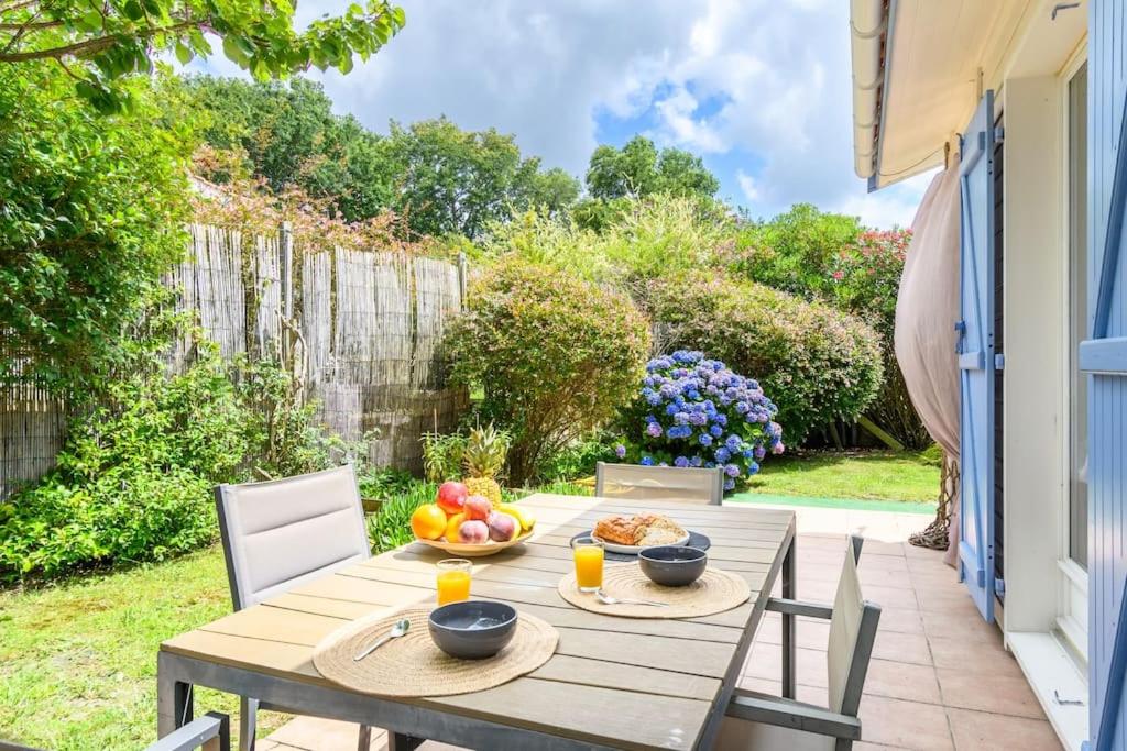- une table en bois avec un bol de fruits sur la terrasse dans l'établissement New Charmante maison proche océan, à Biscarrosse