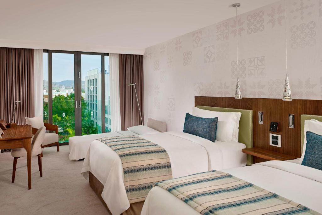 a hotel room with three beds and a desk at Parklane, a Luxury Collection Resort & Spa, Limassol in Limassol