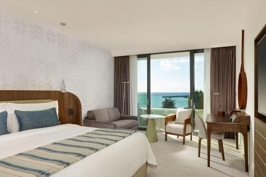 a hotel room with a bed and a desk and a view at Parklane, a Luxury Collection Resort & Spa, Limassol in Limassol