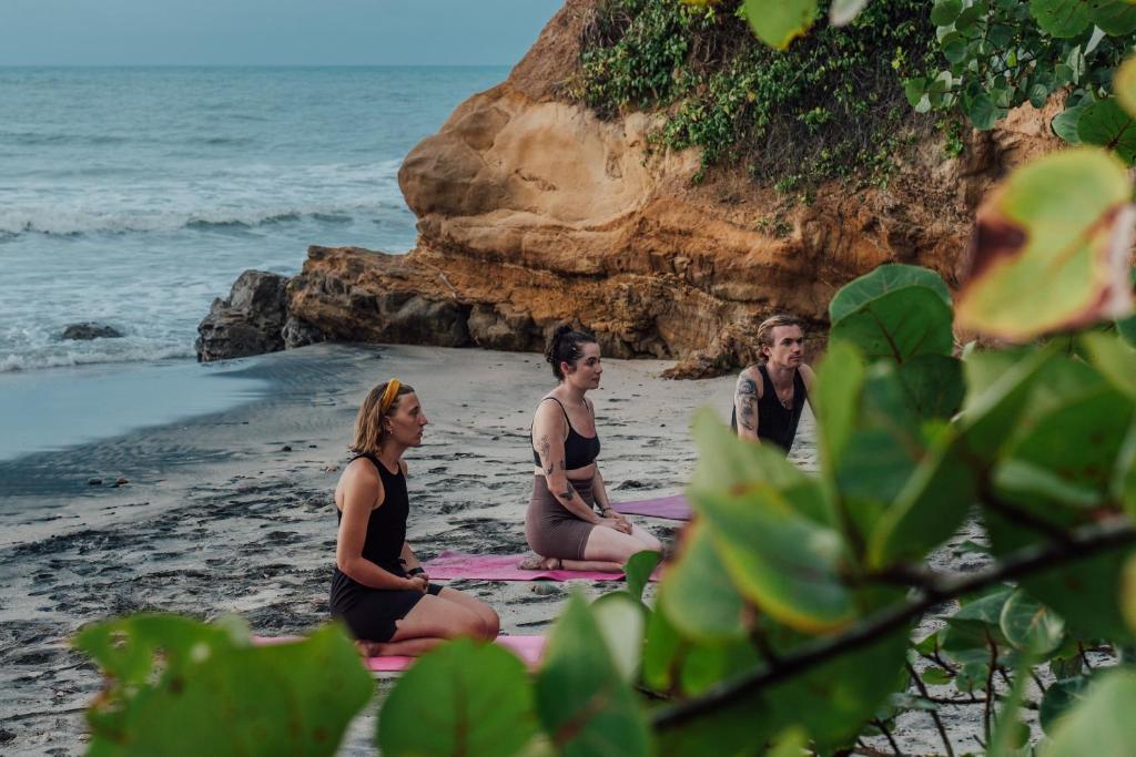 three people sitting on a towel on the beach at Jaba Jan Hostal in Palomino