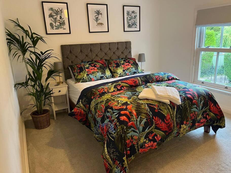 een slaapkamer met een bed met een kleurrijke sprei en een plant bij Chic 2 bedroom cottage in Willingham