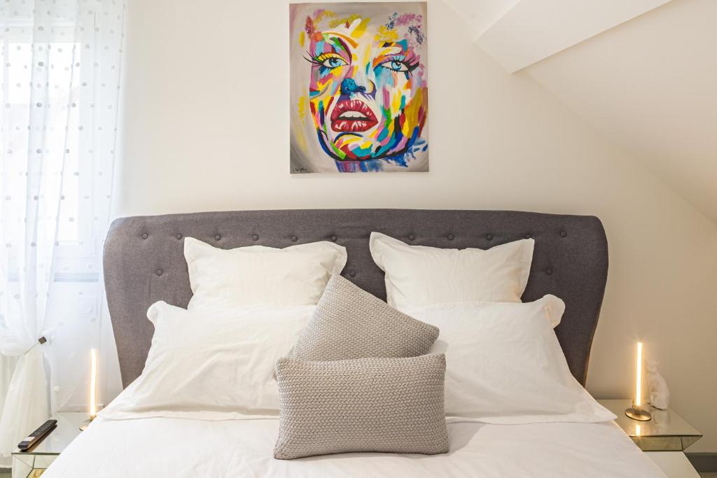 a bed with white pillows and a painting on the wall at Le Flamboyant - Confort &amp; Rareté - Premium in Saint-André-les-Vergers