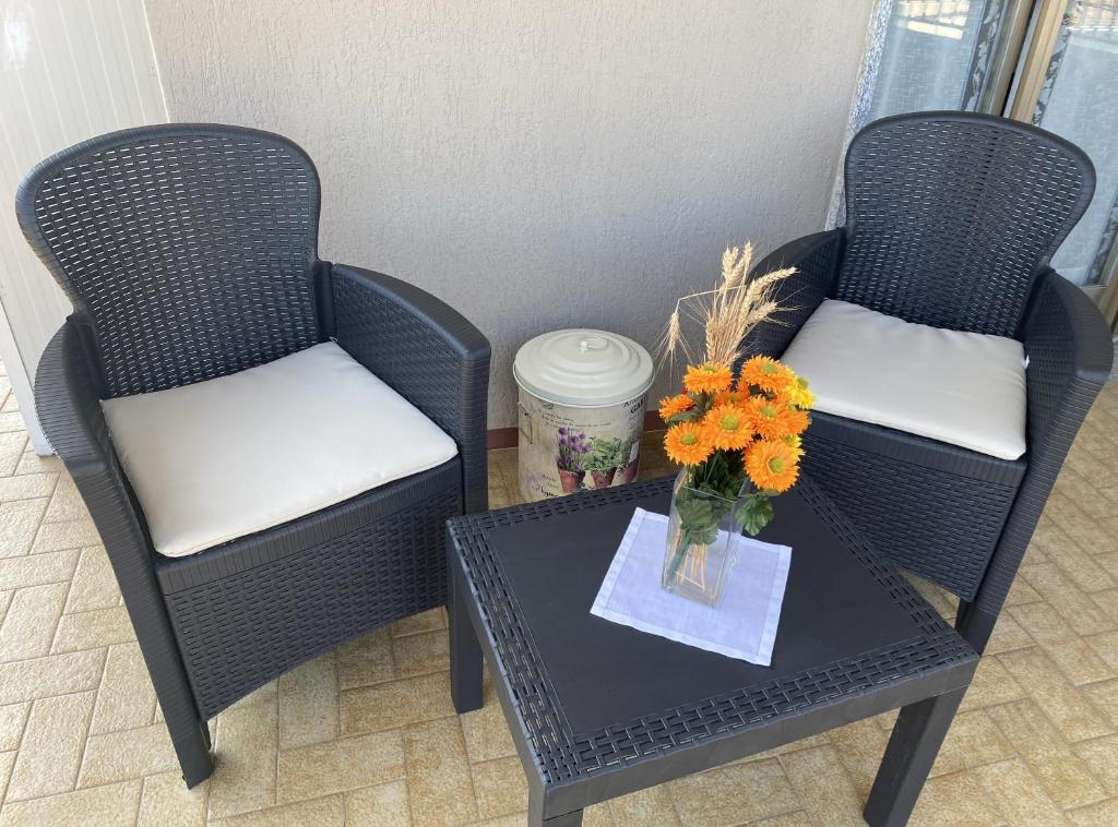 duas cadeiras e uma mesa com um vaso de flores em SANT'ANNA SWEET HOME AI CONFINI DELLE LANGHE em Narzole