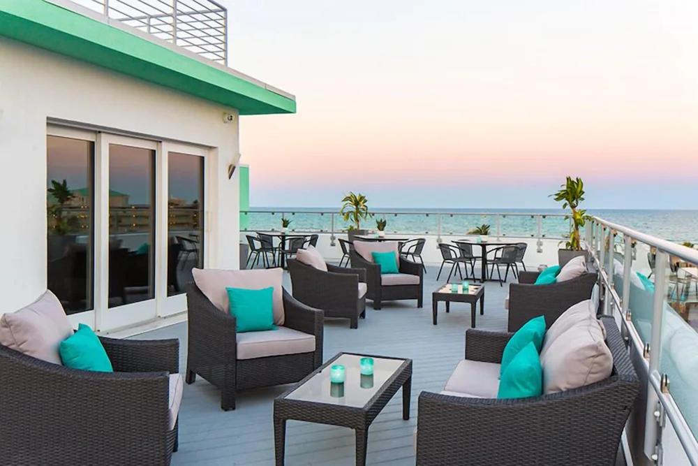 a deck with chairs and tables on the beach at The Streamline Hotel - Daytona Beach in Daytona Beach