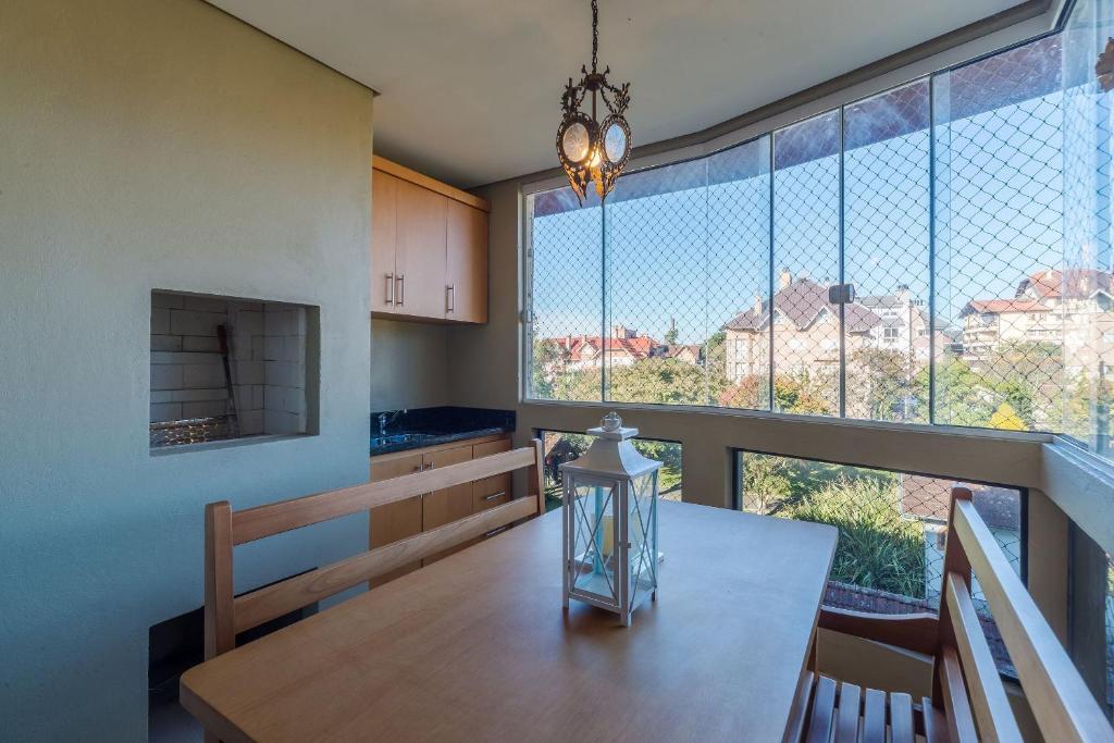 uma cozinha com uma mesa de jantar e janelas grandes em Apto com varanda gourmet em Canela CBL307 em Canela