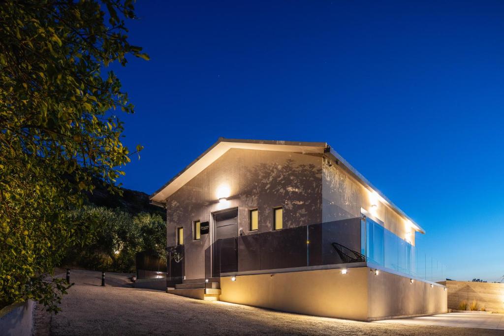 a house with a glass facade at night at ÉTHAFOS Luxury Apartment in Tsikalariá