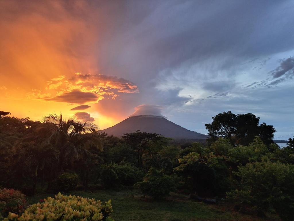 a mountain with a sunset in the background at Hostel Santa Cruz Ometepe in Altagracia