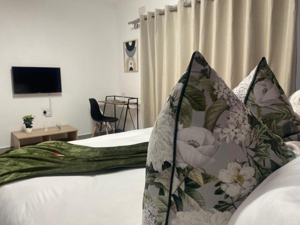 1 dormitorio con 1 cama con sábanas blancas y almohadas florales en Urban & Comfortable Loft apartment in Mthatha, en Mthatha