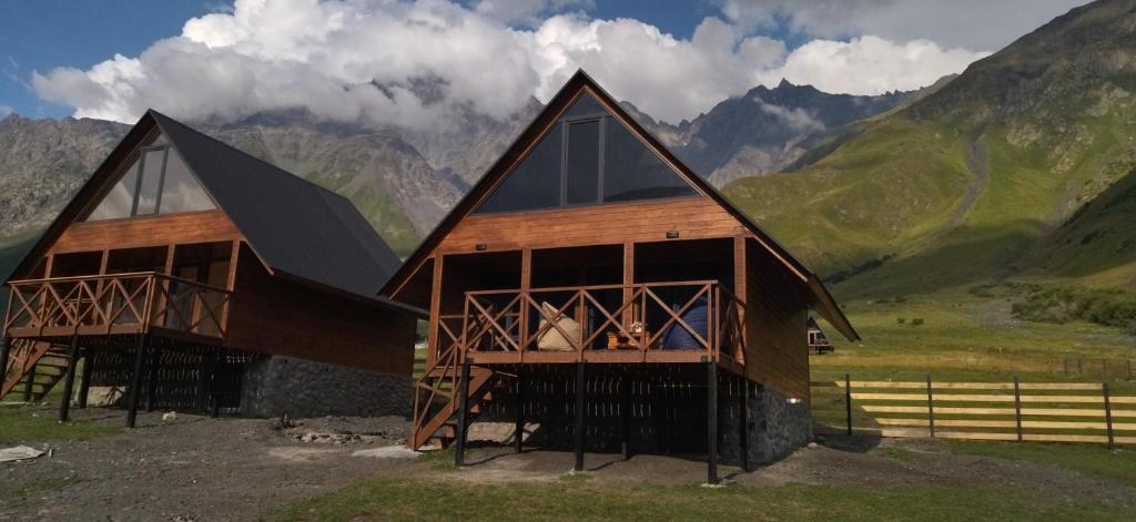 ein Haus auf einem Hügel mit Bergen im Hintergrund in der Unterkunft Cliffside cottage Kazbegi in Kazbegi