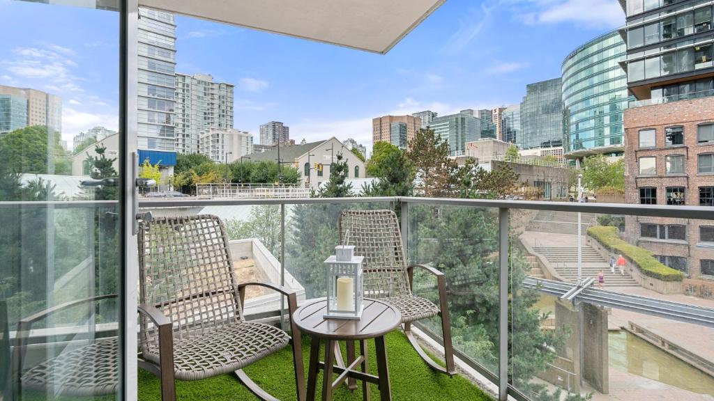 a balcony with two chairs and a table with a candle on it at El Tesoro in the Heart of Van w/ Air Con, Pool, and Free Parking in Vancouver