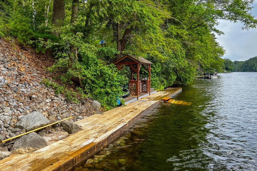 uma doca de madeira com um gazebo ao lado de um rio em Riverfront Log Cabin on the Hudson with Private Dock em Lake Luzerne