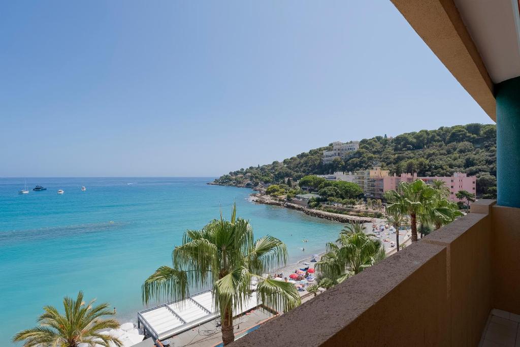 a view of the beach from the balcony of a resort at La Rose des Vents - Sea View in Roquebrune-Cap-Martin