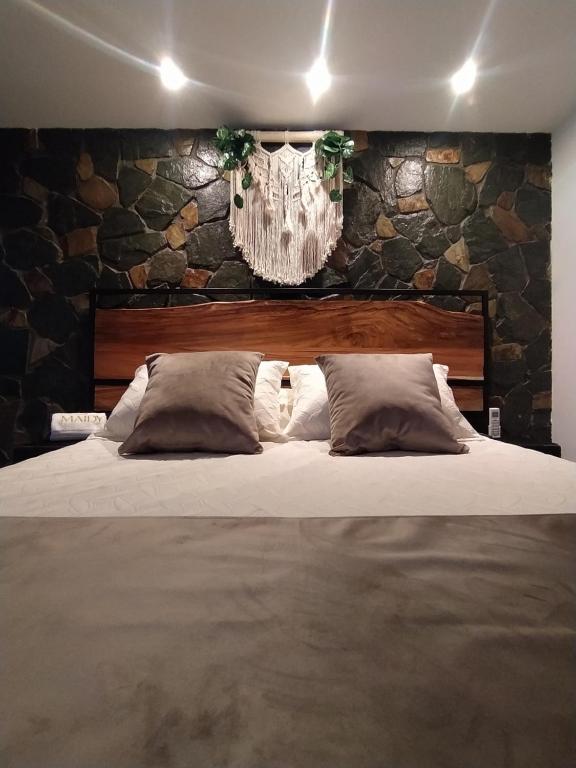 1 dormitorio con 1 cama grande y pared de piedra en Maidy Luxury, en Medellín