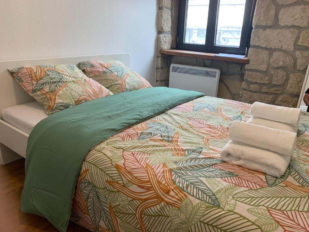 a bed with a colorful comforter and towels on it at Private Room in the City Centre in Esch-sur-Alzette