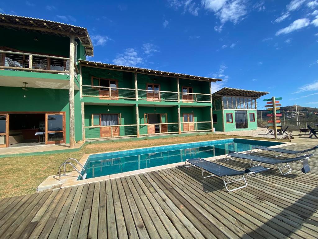 a house with a swimming pool next to a wooden deck at Pousada Recanto Mandalah in Cunha