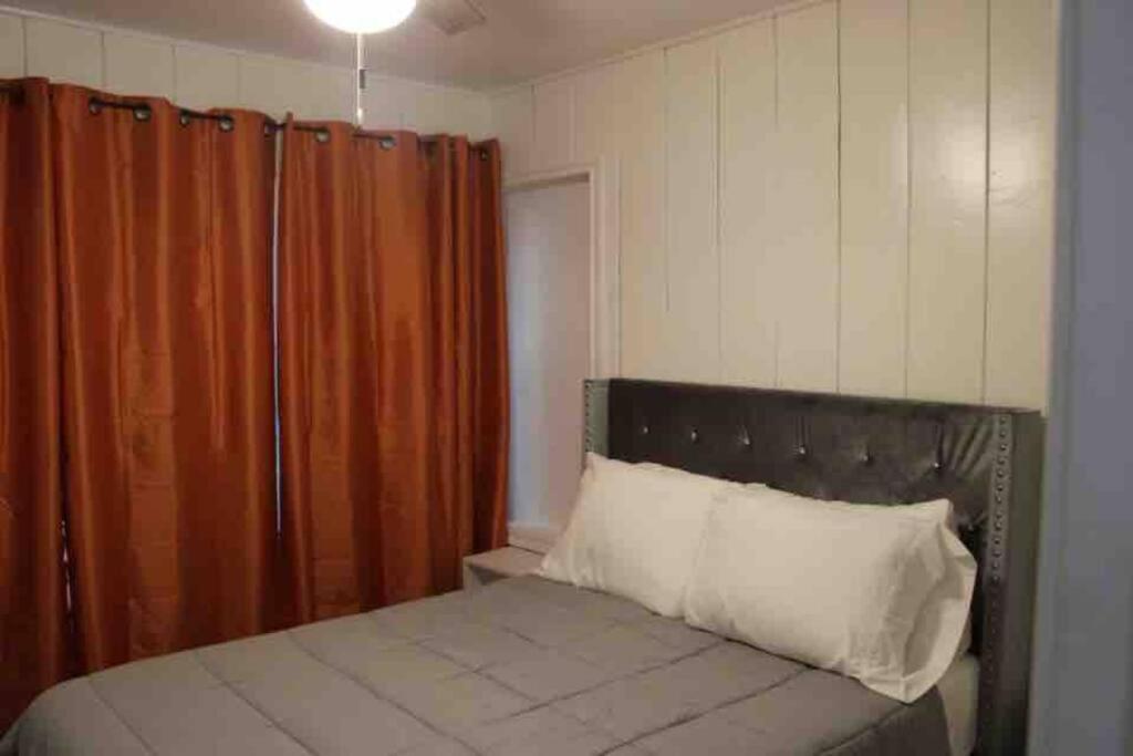 a bedroom with a bed with an orange curtain at Cozy House Downtown Houston! in Houston