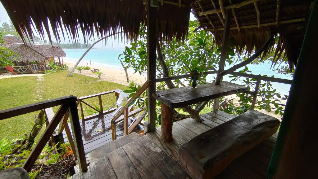 a porch of a hut with a bench on the beach at Serenity Treehouse in Port Olry