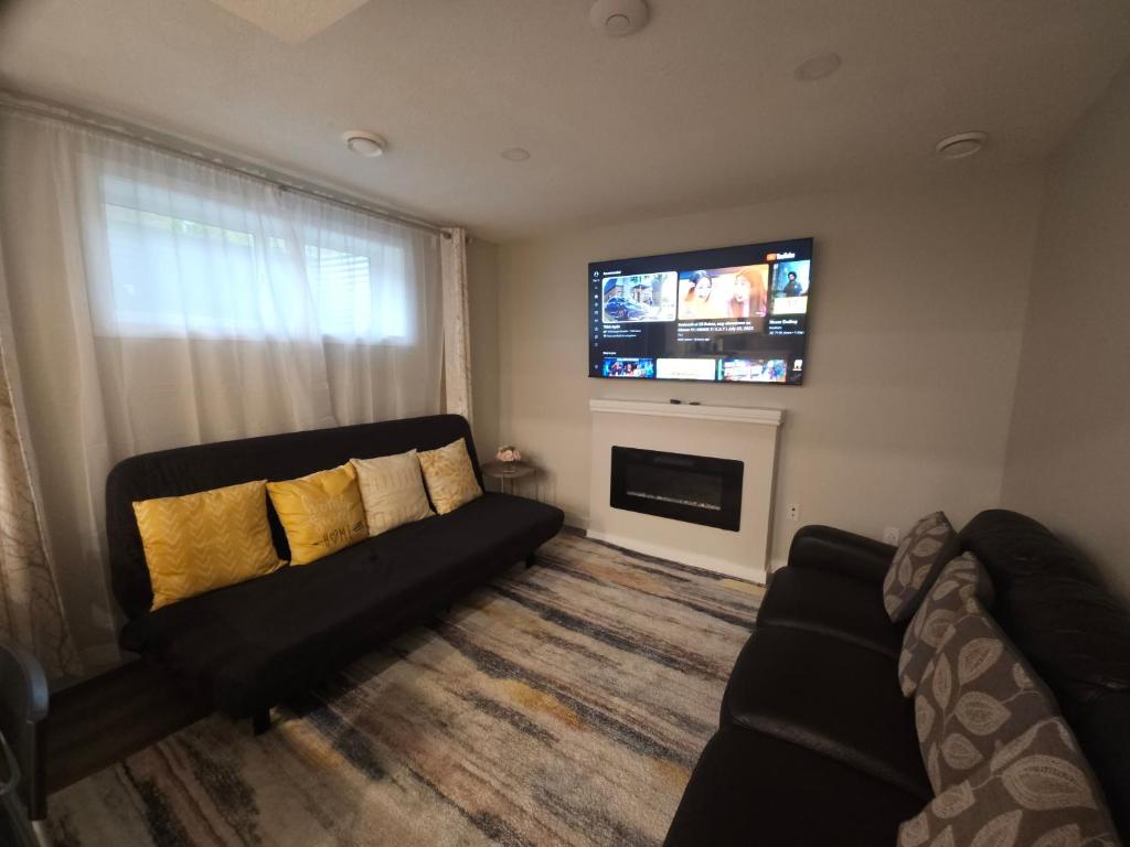 a living room with a couch and a flat screen tv at Cozy 2 Bedroom Suite, Queen Beds, Near the Airport in Edmonton