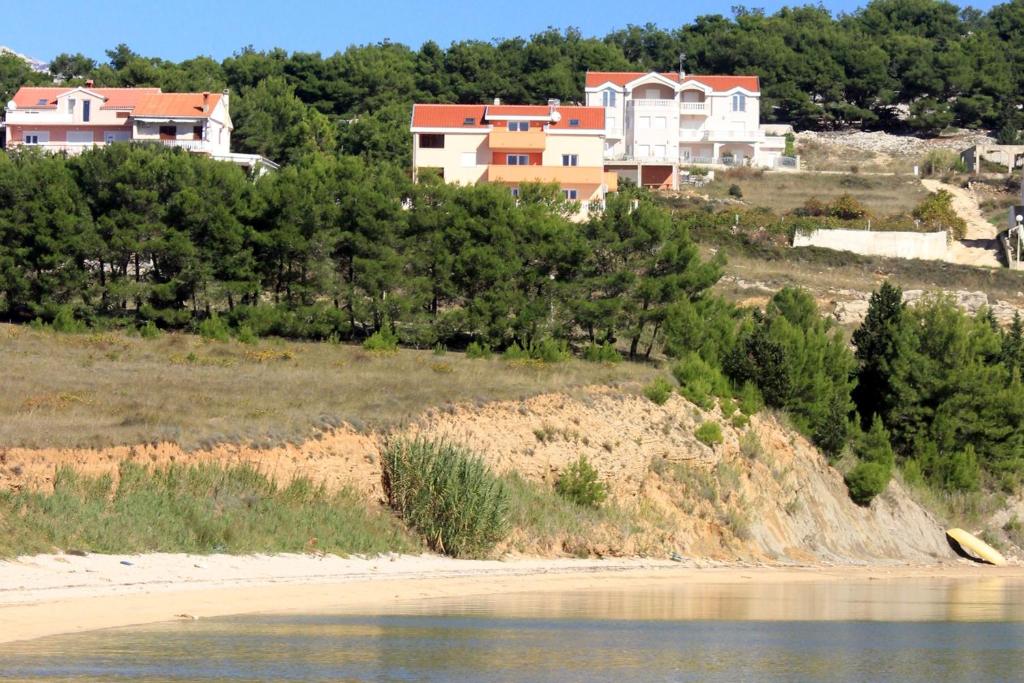 um grupo de casas numa colina junto a uma praia em Apartments by the sea Vlasici, Pag - 9324 em Vlasici